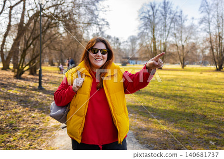 Close up of cheerful young girl pointing away while standing at the park Close up of cheerful young girl pointing away while standing at the park 140681737