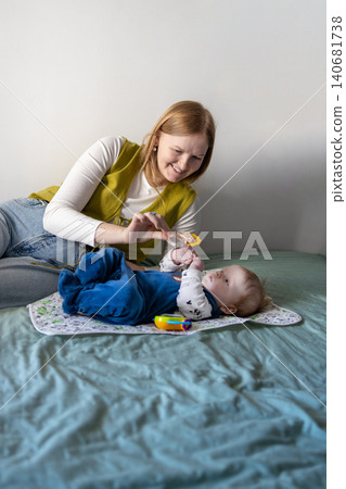 Young mother taking care of her baby boy on a bed at home. Young mother taking care of her baby boy on a bed at home. 140681738
