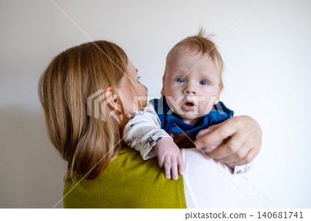 Happy young mother holding her cute baby boy on a light background with copy space. Happy young mother holding her cute baby boy on a light background with copy space. 140681741