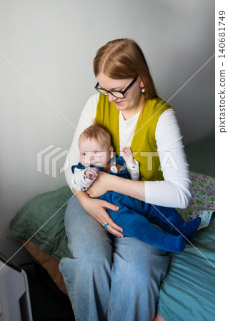 Portrait of a happy smiling mother bottle-feeding her infant baby at home. Portrait of a happy smiling mother bottle-feeding her infant baby at home. 140681749