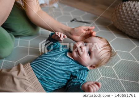 Mother cutting her smiling baby boy's hair with scissors at home Mother cutting her smiling baby boy's hair with scissors at home 140681761