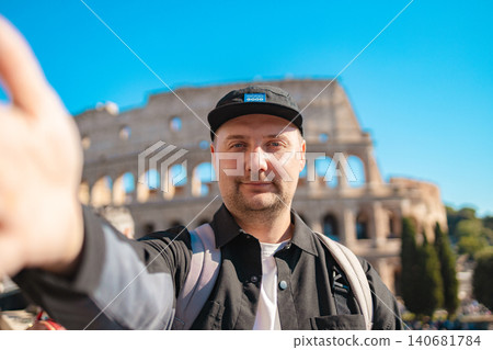 Handsome 30s tourist visiting Colosseum in Rome, Italy. Young man taking photo in front of famous Italian landmark Handsome 30s tourist visiting Colosseum in Rome, Italy. Young man taking photo in front of famous Italian landmark 140681784