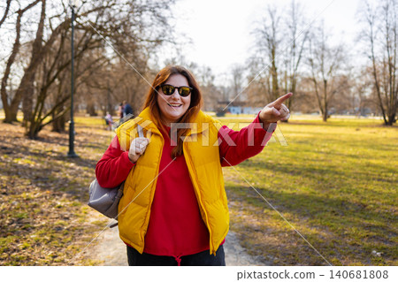 Close up of cheerful young girl pointing away while standing at the park  140681808