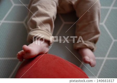 Close-up of cute baby feet resting on a red cushion at home Close-up of cute baby feet resting on a red cushion at home 140681817