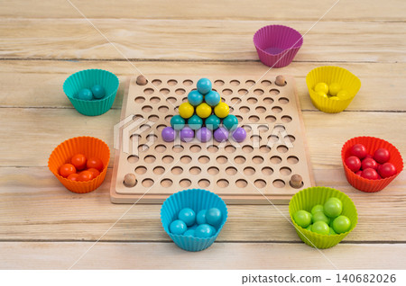 colorful ball pyramid on wooden board, game developing logic and thinking in child, balls arranged in structured pattern, educational activity, learning through play, bright colors, closeup detail 140682026