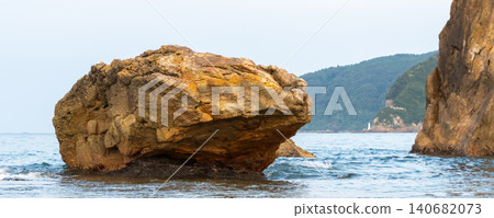 A landscape of rugged, gigantic, strangely shaped rocks floating in a calm sea. A landscape of rugged, gigantic, strangely shaped rocks floating in a calm sea. 140682073
