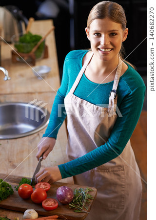 Food, cooking and woman with vegetables in kitchen cutting ingredients with knife at home. Happy, groceries and portrait of female person with produce for dinner, supper or meal at apartment. 140682270