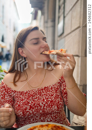 Happy young woman eating delicious Italian pizza at outdoor cafe in Europe Happy young woman eating delicious Italian pizza at outdoor cafe in Europe 140682312