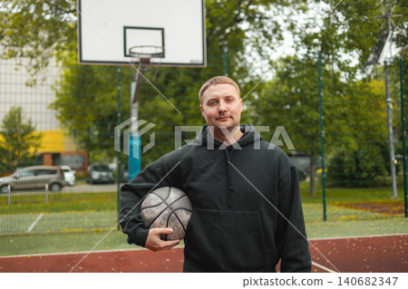 Portrait of smiling man holding basketball ball on court Portrait of smiling man holding basketball ball on court 140682347