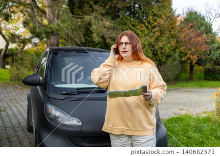 Woman talking on phone calling roadside assistance near car Woman talking on phone calling roadside assistance near car 140682371
