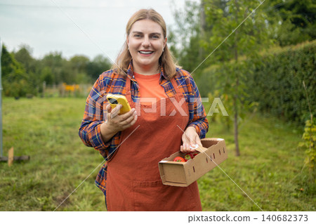 Happy young woman farmer holding strawberry box in garden Happy young woman farmer holding strawberry box in garden 140682373