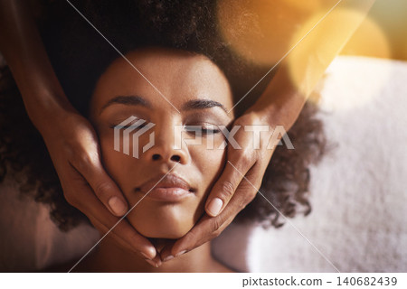 Woman, relax and massage on face with hands and care for facial, wellness and spa treatment on bed. Above, lens flare and african female person with skincare and cosmetics at hotel with skin glow Woman, relax and massage on face with hands and care for facial, wellness and spa treatment on bed. Above, lens flare and african female person with skincare and cosmetics at hotel with skin glow 140682439