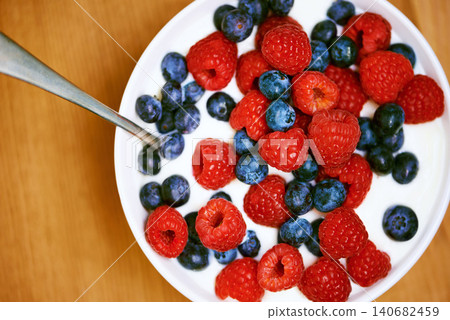 High angle, berries and nutrition with yogurt, raspberry and blueberry for organic snack. Food, cuisine and breakfast for health, wellness and diet for morning bowl or antioxidant wellbeing in studio High angle, berries and nutrition with yogurt, raspberry and blueberry for organic snack. Food, cuisine and breakfast for health, wellness and diet for morning bowl or antioxidant wellbeing in studio 140682459