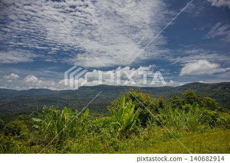 Tropical mountain rainforest valley cloud sky forest panorama, wide landscape view over lush green ridge and grass with banana plant under dramatic summer clouds, peaceful mood Tropical mountain rainforest valley cloud sky forest panorama, wide landscape view over lush green ridge and grass with banana plant under dramatic summer clouds, peaceful mood 140682914