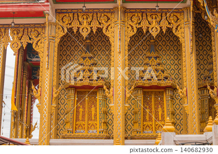 Golden temple facade Thai architecture ornate carving pattern window mosaic detail, rich gilded decoration with repeating geometric motif and sacred design under daylight Golden temple facade Thai architecture ornate carving pattern window mosaic detail, rich gilded decoration with repeating geometric motif and sacred design under daylight 140682930