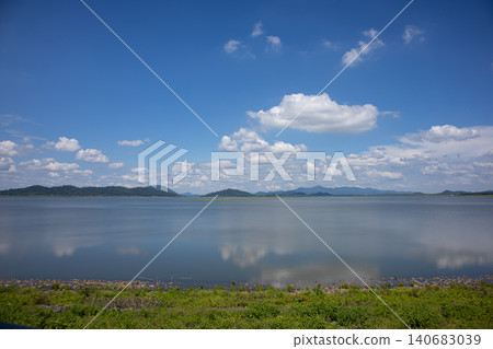Lake calm water blue sky cloud mountain horizon reflection shoreline, wide tranquil landscape with distant ridge, summer daylight, open space for travel nature background Lake calm water blue sky cloud mountain horizon reflection shoreline, wide tranquil landscape with distant ridge, summer daylight, open space for travel nature background 140683039