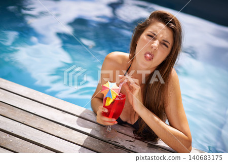 Woman, funny and portrait with cocktail in swimming pool with tongue out for goofy behavior, luxury and resort. Girl, summer and tropical vacation or holiday in Maldives with beverage for sunbathing. Woman, funny and portrait with cocktail in swimming pool with tongue out for goofy behavior, luxury and resort. Girl, summer and tropical vacation or holiday in Maldives with beverage for sunbathing. 140683175