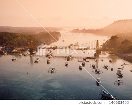 Drone view of a bridge connecting two islands over ocean. Nusa Lembongan and Nusa Ceningan bridge with boats. Drone view of a bridge connecting two islands over ocean. Nusa Lembongan and Nusa Ceningan bridge with boats. 140683493