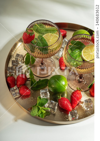 Strawberry lime mojito cocktails on gold tray with ice and mint Strawberry lime mojito cocktails on gold tray with ice and mint 140683612