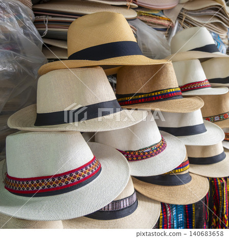 Close-up of handcrafted Ecuadorian toquilla straw hats stacked at a market stall. Close-up of handcrafted Ecuadorian toquilla straw hats stacked at a market stall. 140683658