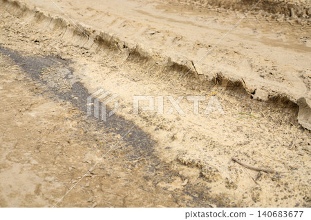 Deep tire tracks imprinted on dry mud road surface, textured car wheel tread marks on country ground path close up Deep tire tracks imprinted on dry mud road surface, textured car wheel tread marks on country ground path close up 140683677