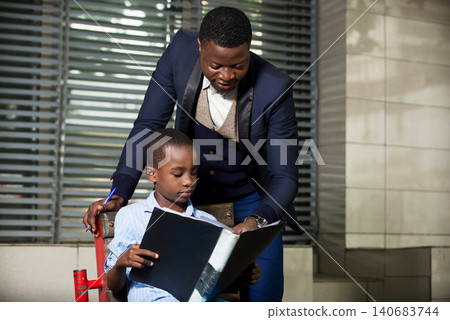 Businessman reading a book to his child outdoors Businessman reading a book to his child outdoors 140683744