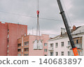 Mobile crane lifting construction materials at residential building renovation site 140683897