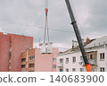 Mobile crane lifting construction materials at residential building renovation site 140683900
