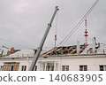 Mobile crane lifting construction materials during roof renovation of residential building 140683905