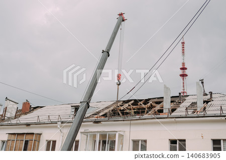 Mobile crane lifting construction materials during roof renovation of residential building Mobile crane lifting construction materials during roof renovation of residential building 140683905