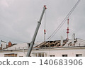Mobile crane lifting construction materials during roof renovation of residential building 140683906