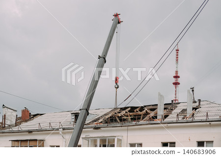 Mobile crane lifting construction materials during roof renovation of residential building Mobile crane lifting construction materials during roof renovation of residential building 140683906