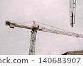 Tower crane at construction site against overcast sky 140683907