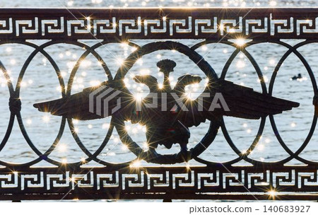 picturesque metal railings with a double-headed eagle and the crown of the Russian Empire on embankment in St. Petersburg, Russia, walking people, sunny autumn day, incredible sun glare Russia picturesque metal railings with a double-headed eagle and the crown of the Russian Empire on embankment in St. Petersburg, Russia, walking people, sunny autumn day, incredible sun glare Russia 140683927