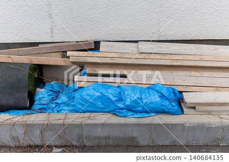 The area around the house is littered with discarded materials and weeds along the exterior walls. The area around the house is littered with discarded materials and weeds along the exterior walls. 140684135