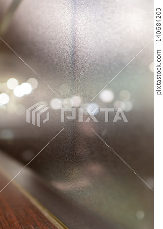Beautiful city lights and a bokeh texture background, seen through frosted glass. Beautiful city lights and a bokeh texture background, seen through frosted glass. 140684203