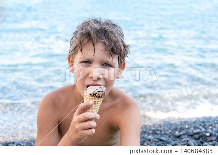 Boy Enjoying Ice Cream Cone by the Sea, Summer Joy and Relaxation Boy Enjoying Ice Cream Cone by the Sea, Summer Joy and Relaxation 140684383