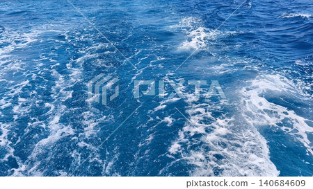 Foamy boat wake trailing across vibrant blue ocean water. Dynamic marine texture capturing movement, travel, adventure and the energy of life at sea Foamy boat wake trailing across vibrant blue ocean water. Dynamic marine texture capturing movement, travel, adventure and the energy of life at sea 140684609