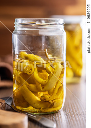 Jar Of Pickled Yellow Peppers In Oil On Wooden Table. Preserved Pepper Condiment Jar Of Pickled Yellow Peppers In Oil On Wooden Table. Preserved Pepper Condiment 140684995