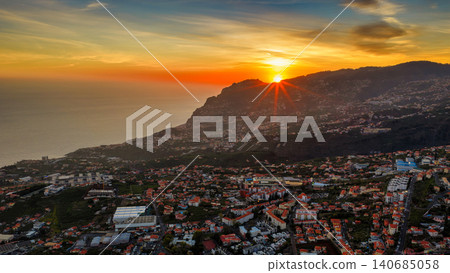 Aerial sunset over coastal city on Madeira Island with sun flare Aerial sunset over coastal city on Madeira Island with sun flare 140685058