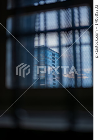 Wire mesh window view toward central Vilnius high rise at dusk Wire mesh window view toward central Vilnius high rise at dusk 140685232