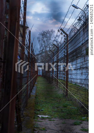 Lukiskes Prison corridor with barbed wire and razor wire at dusk Lukiskes Prison corridor with barbed wire and razor wire at dusk 140685251