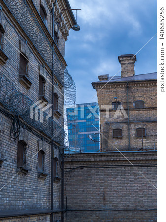 Lukiskes Prison courtyard with razor wire and modern high rise Lukiskes Prison courtyard with razor wire and modern high rise 140685256