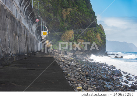 Madeira north coast VE1 tunnel, seawall, and pebble beach in daylight Madeira north coast VE1 tunnel, seawall, and pebble beach in daylight 140685295