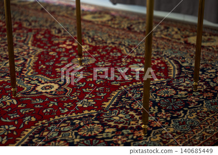 Ornate Persian style rug with brass table legs in Madeira interior Ornate Persian style rug with brass table legs in Madeira interior 140685449