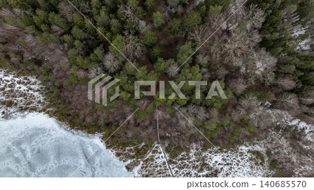 Aerial View of Snow Covered Forest and Frozen Water in Winter 140685570