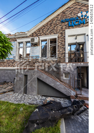 Bila Tserkva, Kyiv region, Ukraine - 09.06.2025: Low angle view of destroyed brick medical clinic building facade with shattered windows broken entrance doors and debris after explosion blast Bila Tserkva, Kyiv region, Ukraine - 09.06.2025: Low angle view of destroyed brick medical clinic building facade with shattered windows broken entrance doors and debris after explosion blast 140685612