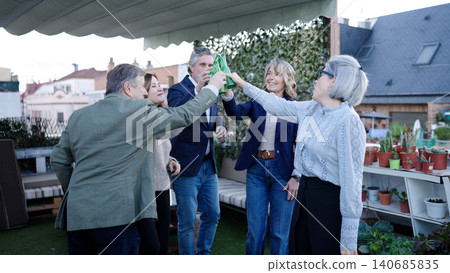 Senior friends toasting beer bottles on rooftop party Senior friends toasting beer bottles on rooftop party 140685835