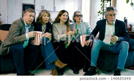 Friends watching exciting movie on TV and reacting together Friends watching exciting movie on TV and reacting together 140685849