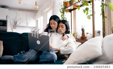 Young women friends bonding with laptop on sofa Young women friends bonding with laptop on sofa 140685863